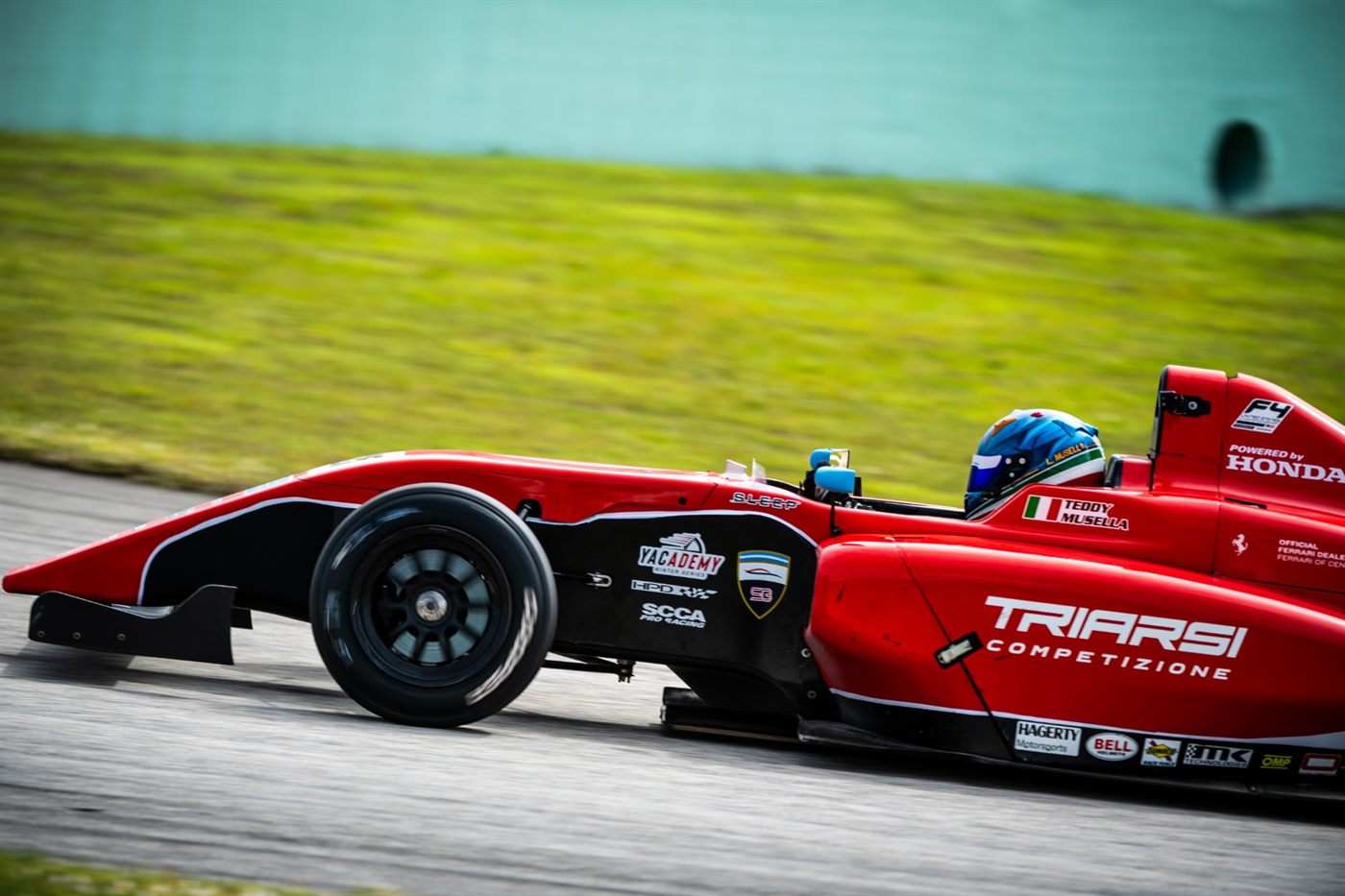 Side profile of the red No. 25 Triarsi Competizione Formula 4 car at Homestead-Miami, with Teddy Musella's name on the cockpit side.